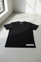 Black blank t-shirt laid flat on a light studio floor near a window, with a “Ready for DTF” label in the corner