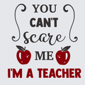 A typographic design on a light gray background reading 'YOU CAN'T scare ME I'M A TEACHER' in black and red lettering, with two red apples and decorative black flourishes.